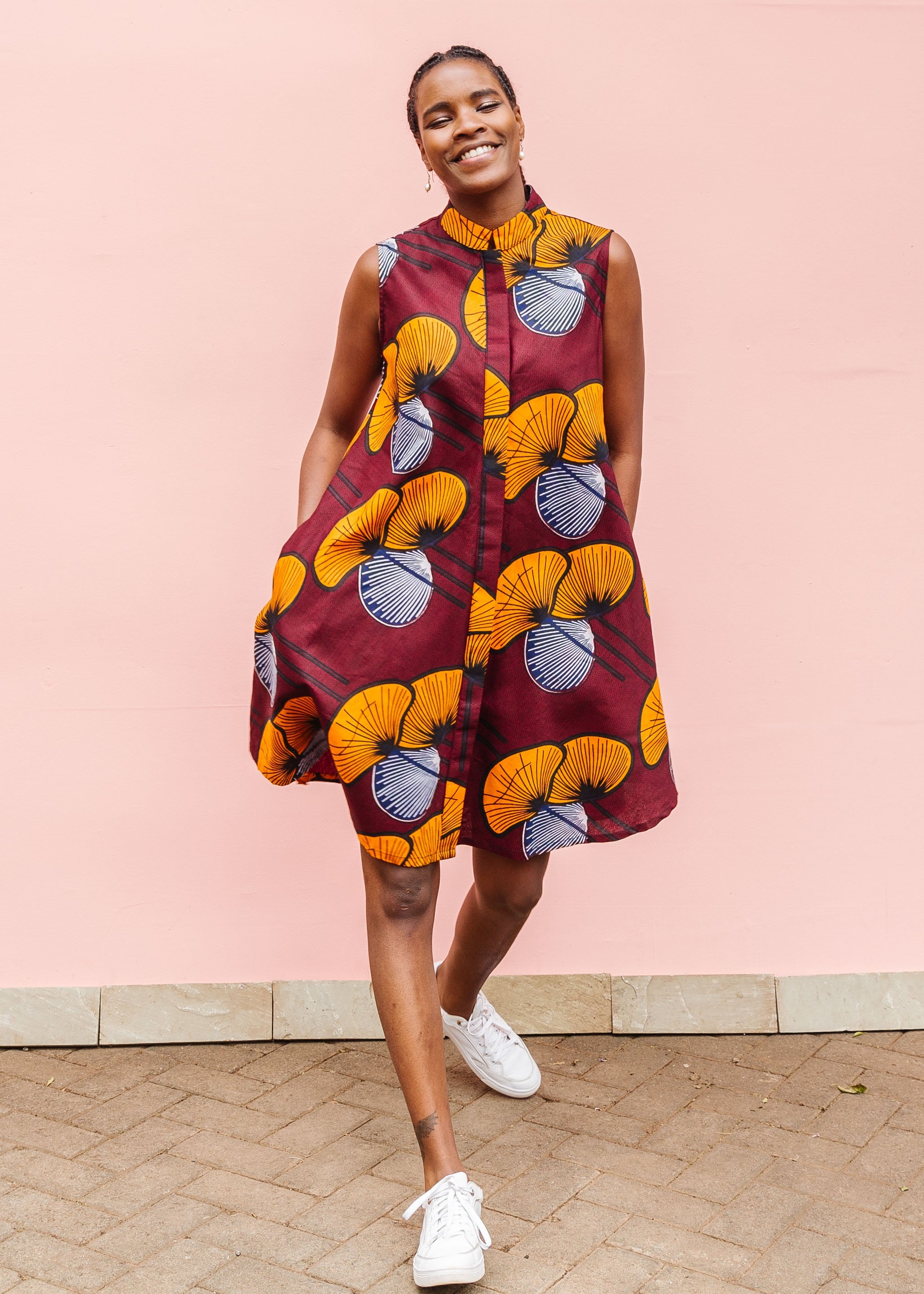 Model wearing burgundy sleeveless dress with yellow and white flowers.