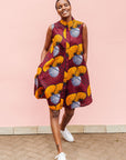 Model wearing burgundy sleeveless dress with yellow and white flowers.