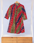 Display of green dress, with bold red and navy bauble print.