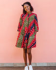 Model wearing green dress, with bold red and navy bauble print.