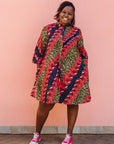 Model wearing green dress, with bold red and navy bauble print.