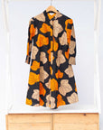 Display of orange, beige and black leaf print dress.