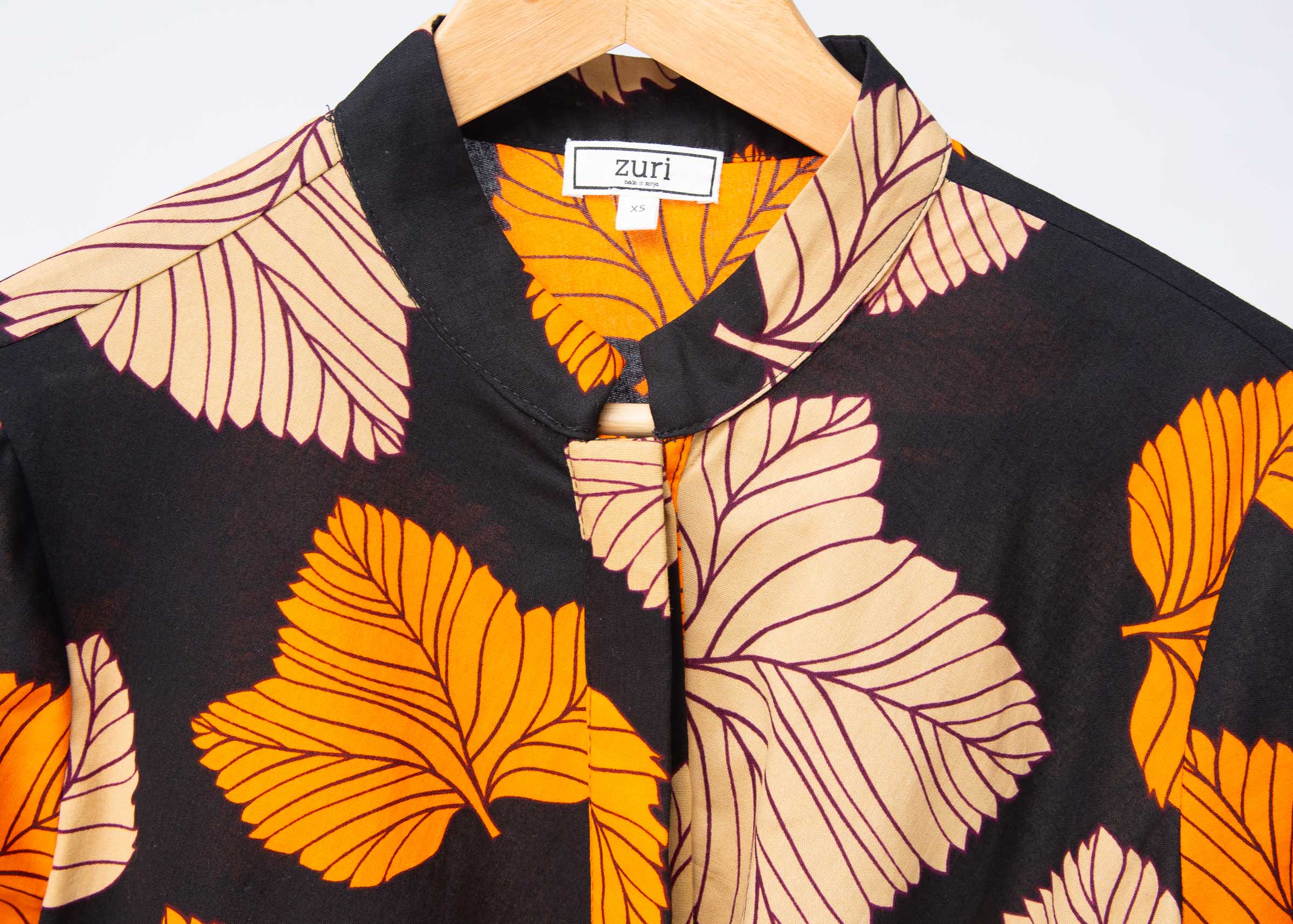 Display of orange, beige and black leaf print dress.