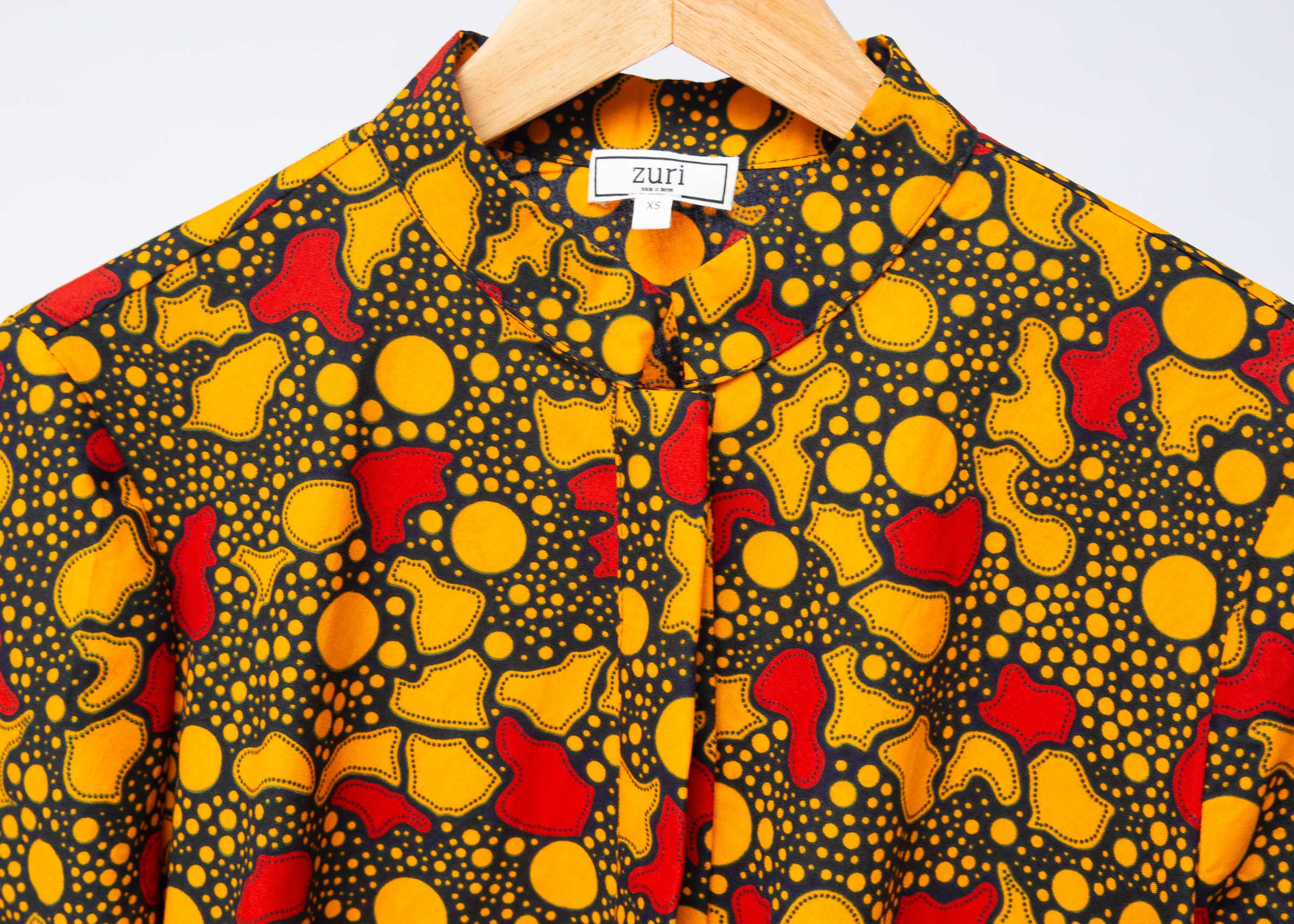 Display of black dress with yellow and red small blob print.