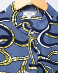 Display of blue sleeveless dress with green, white and navy squiggle design.