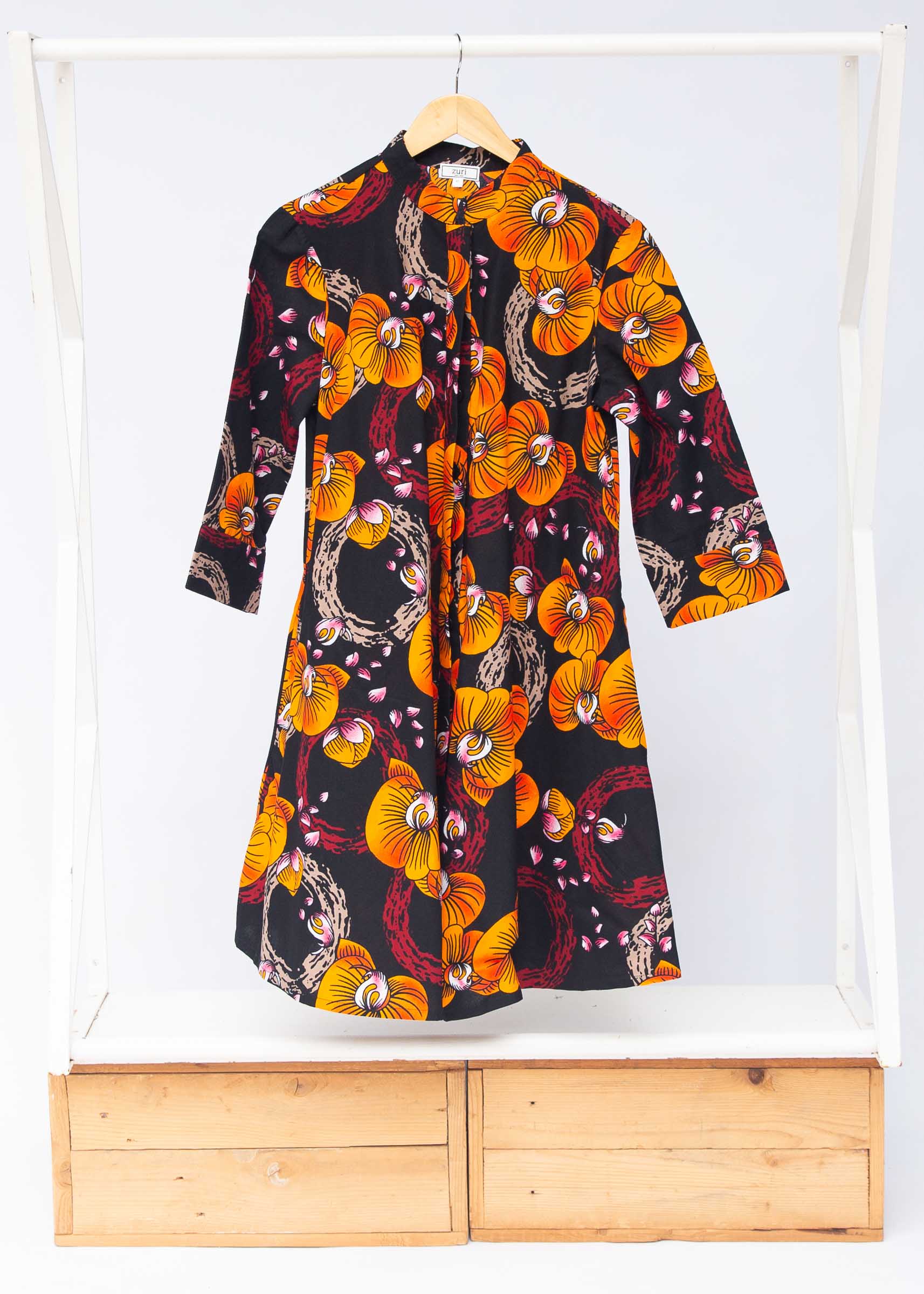 Display of black dress with yellow and pink floral print.