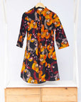 Display of black dress with yellow and pink floral print.