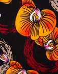 Close up display of black dress with yellow and pink floral print, fabric.