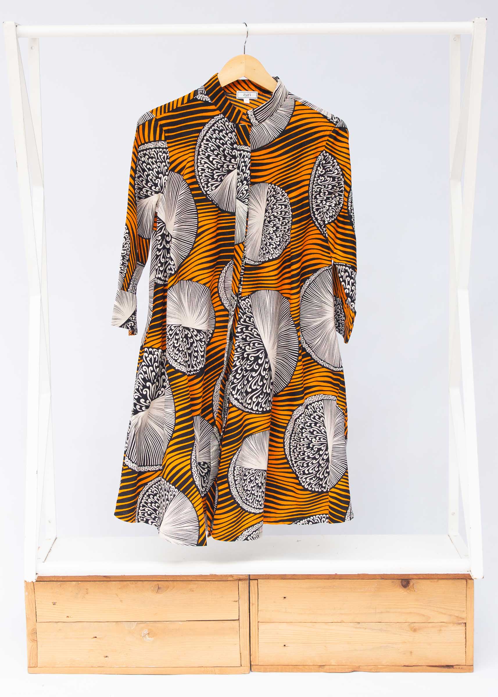 Display of black dress with orange stripes and black and white circles.