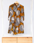 Display of black dress with orange stripes and black and white circles.