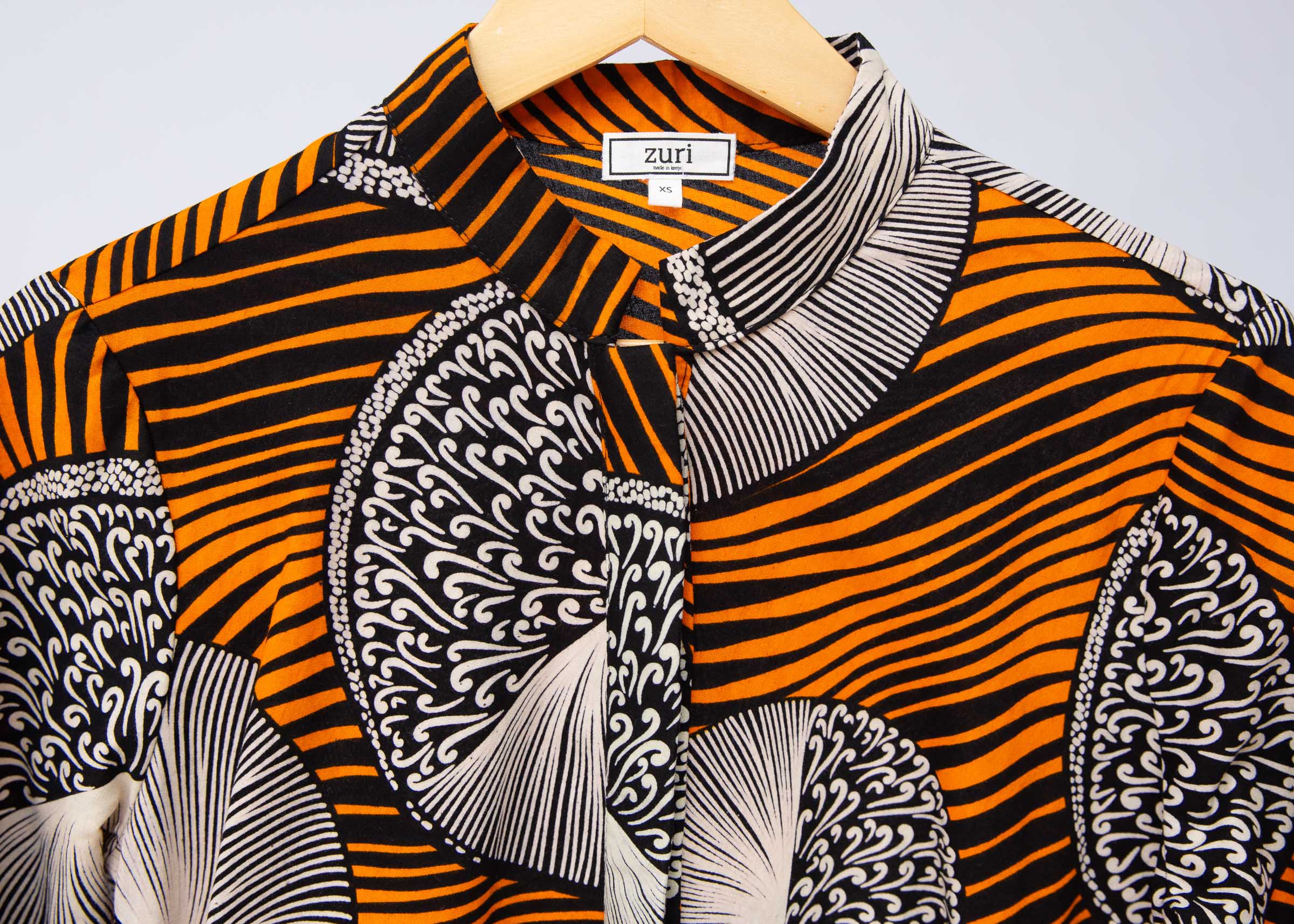 Display of black dress with orange stripes and black and white circles.
