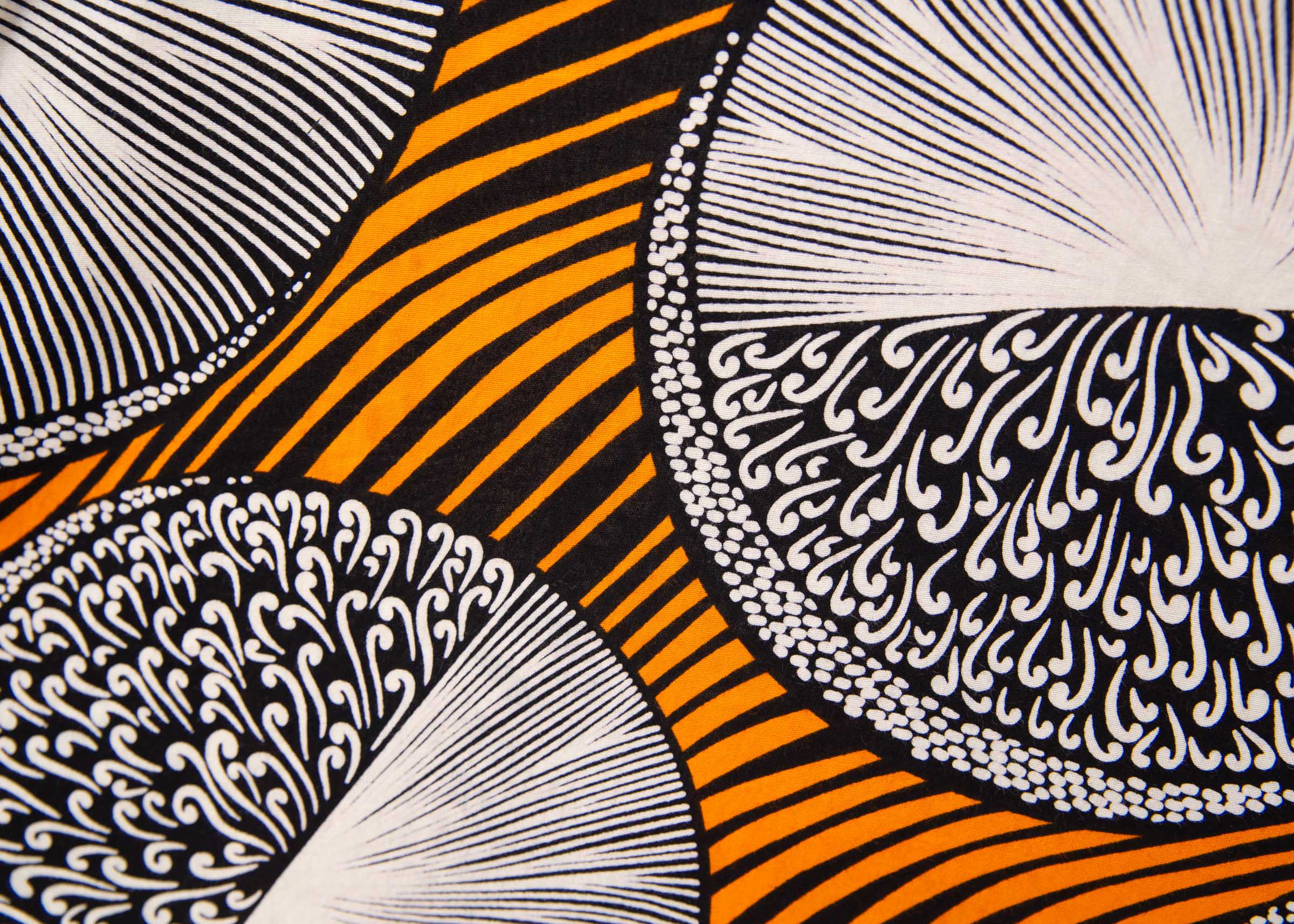 Close up display of black dress with orange stripes and black and white circles, fabric.