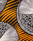 Close up display of black dress with orange stripes and black and white circles, fabric.
