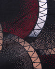 Close up display of red, beige, white and black geometric print dress, fabric.