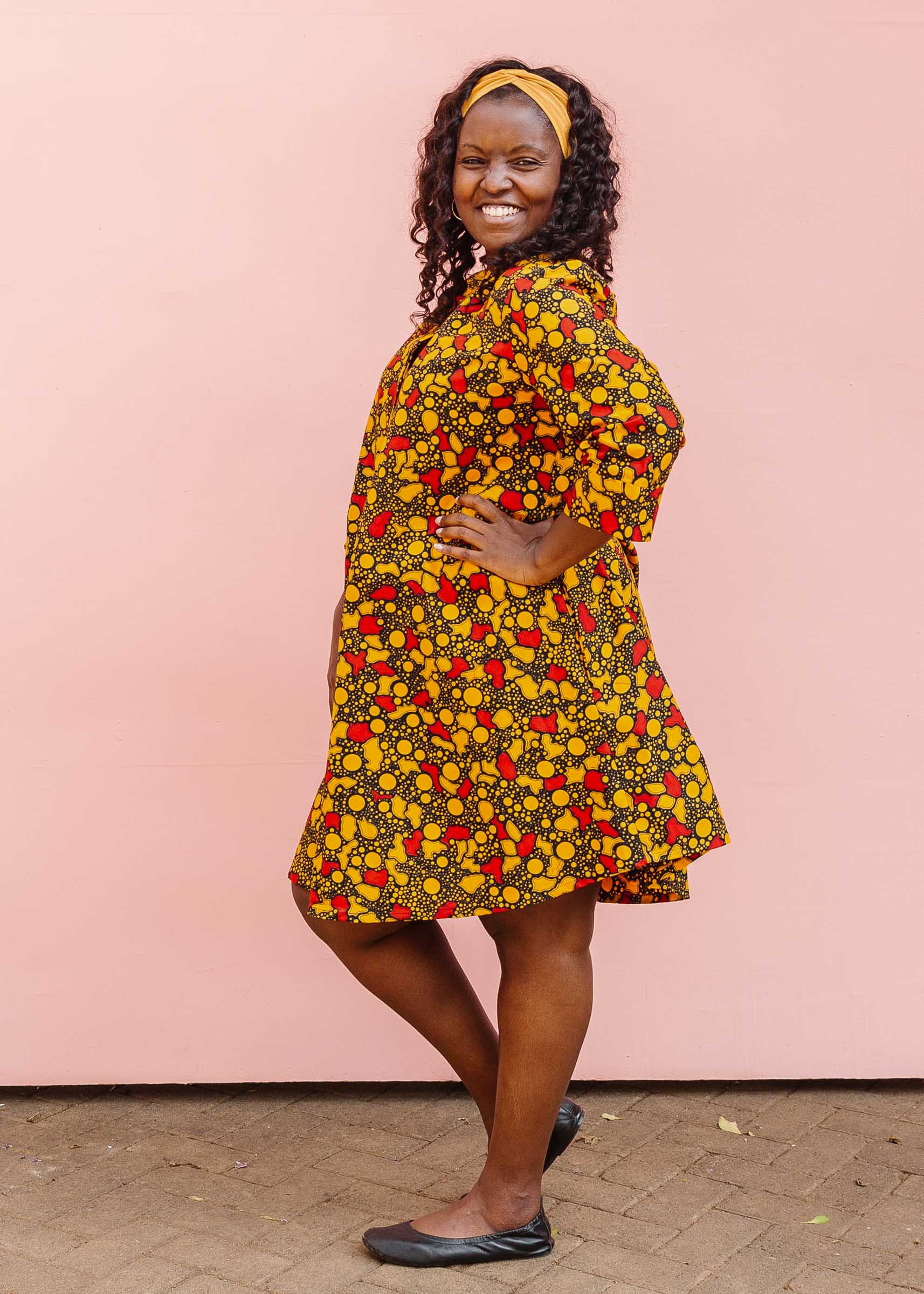 The model is wearing black dress with yellow and red small blob print.