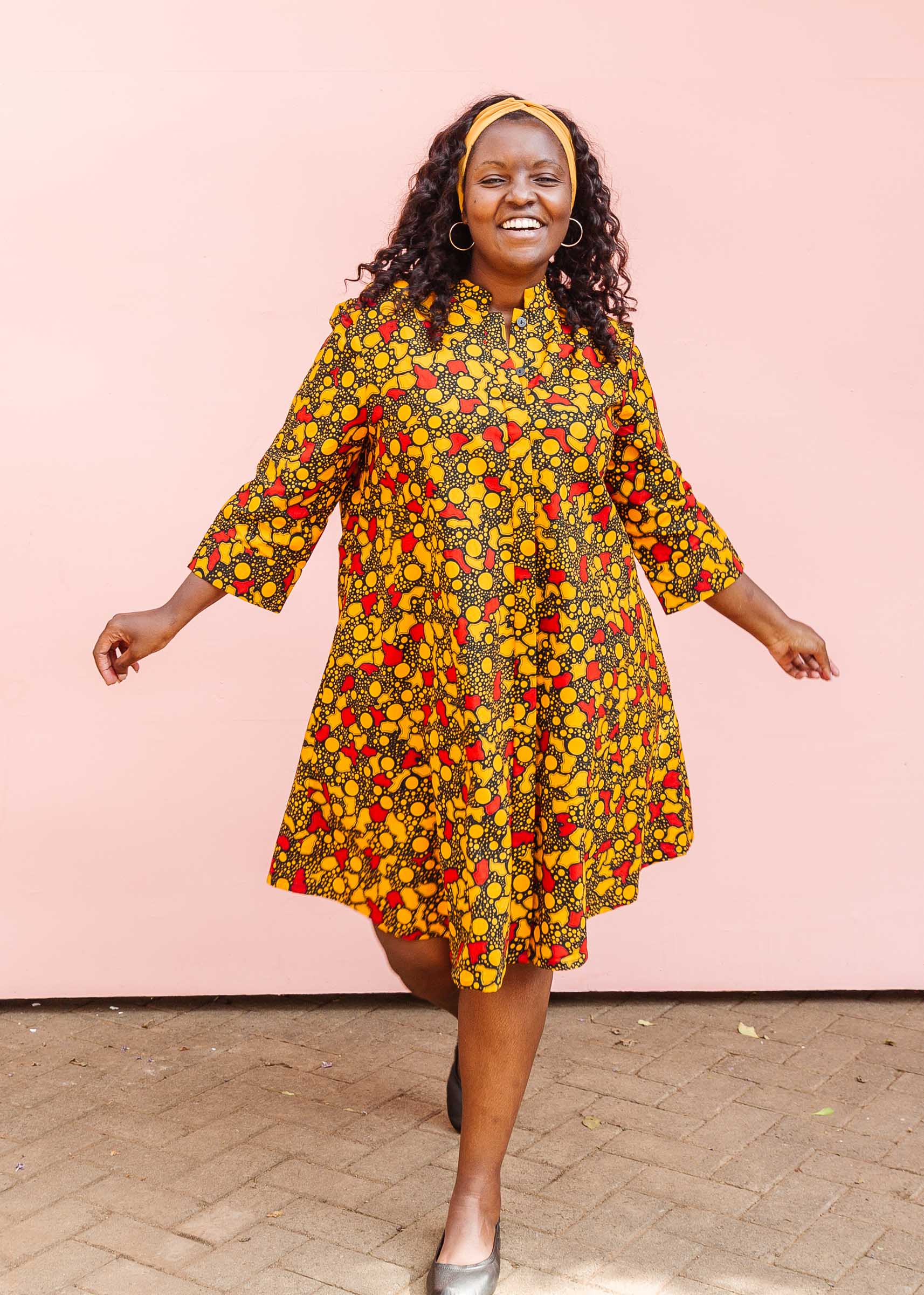 The model is wearing black dress with yellow and red small blob print.