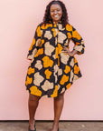 Model wearing orange, beige and black leaf print dress.