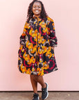 The model is wearing black dress with yellow and pink floral print.