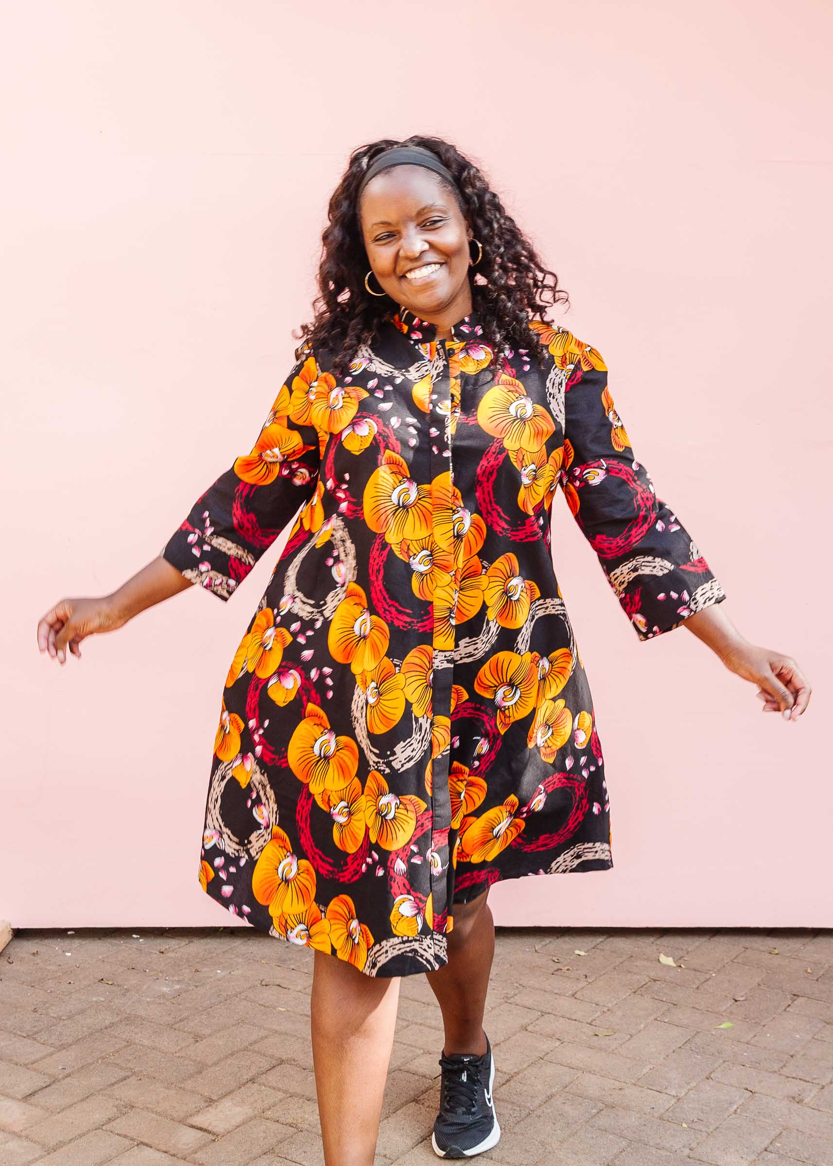 The model is wearing black dress with yellow and pink floral print.