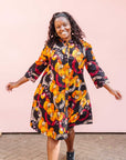 The model is wearing black dress with yellow and pink floral print.