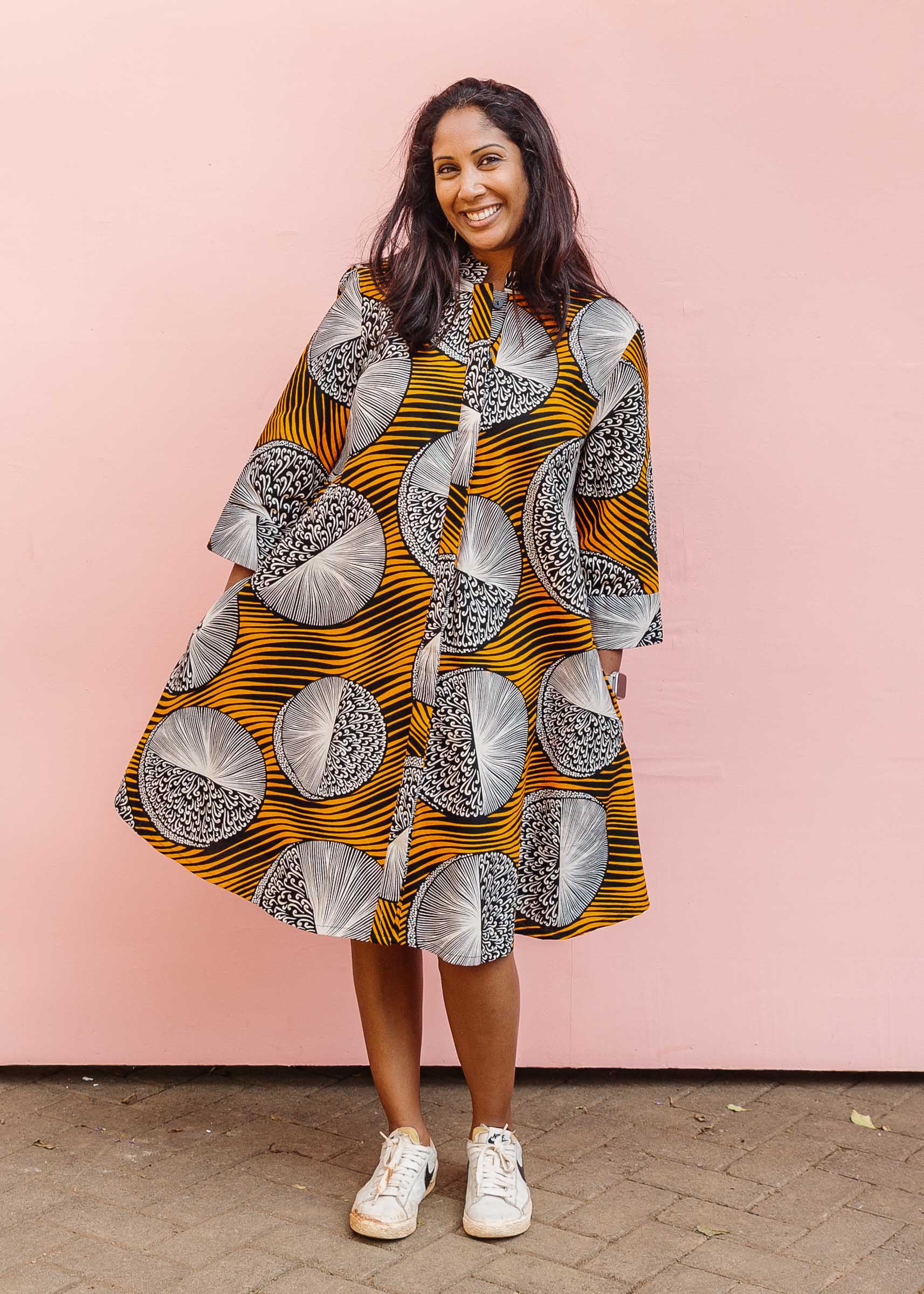 Model wearing black dress with orange stripes and black and white circles.