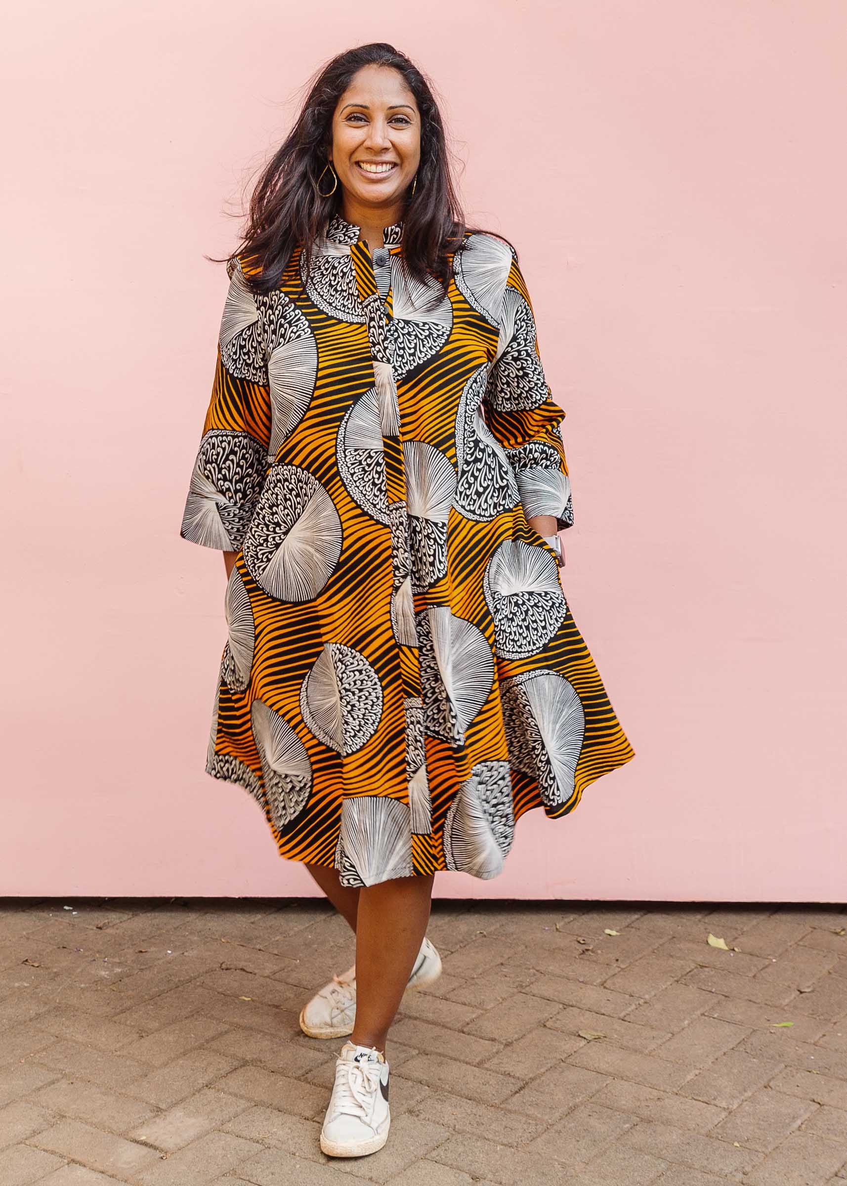 Model wearing black dress with orange stripes and black and white circles.