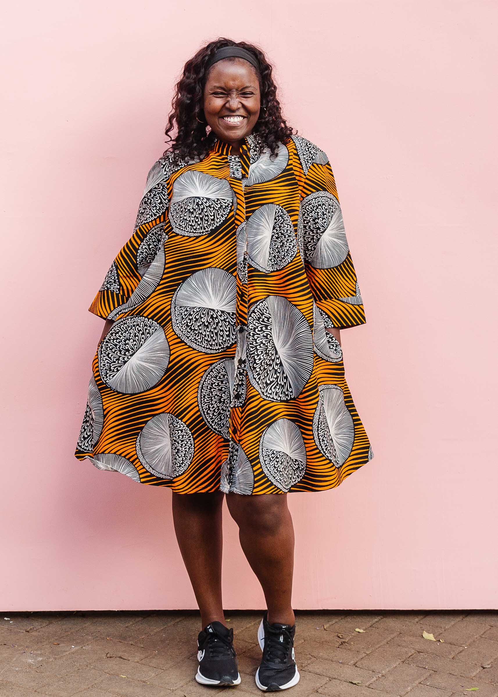 Model wearing black dress with orange stripes and black and white circles.