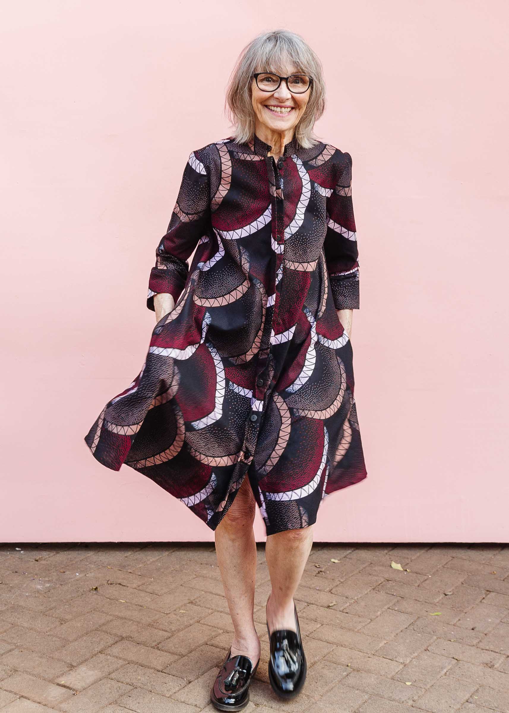 Model wearing red, beige, white and black geometric print dress.
