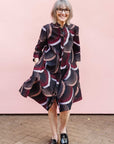 Model wearing red, beige, white and black geometric print dress.