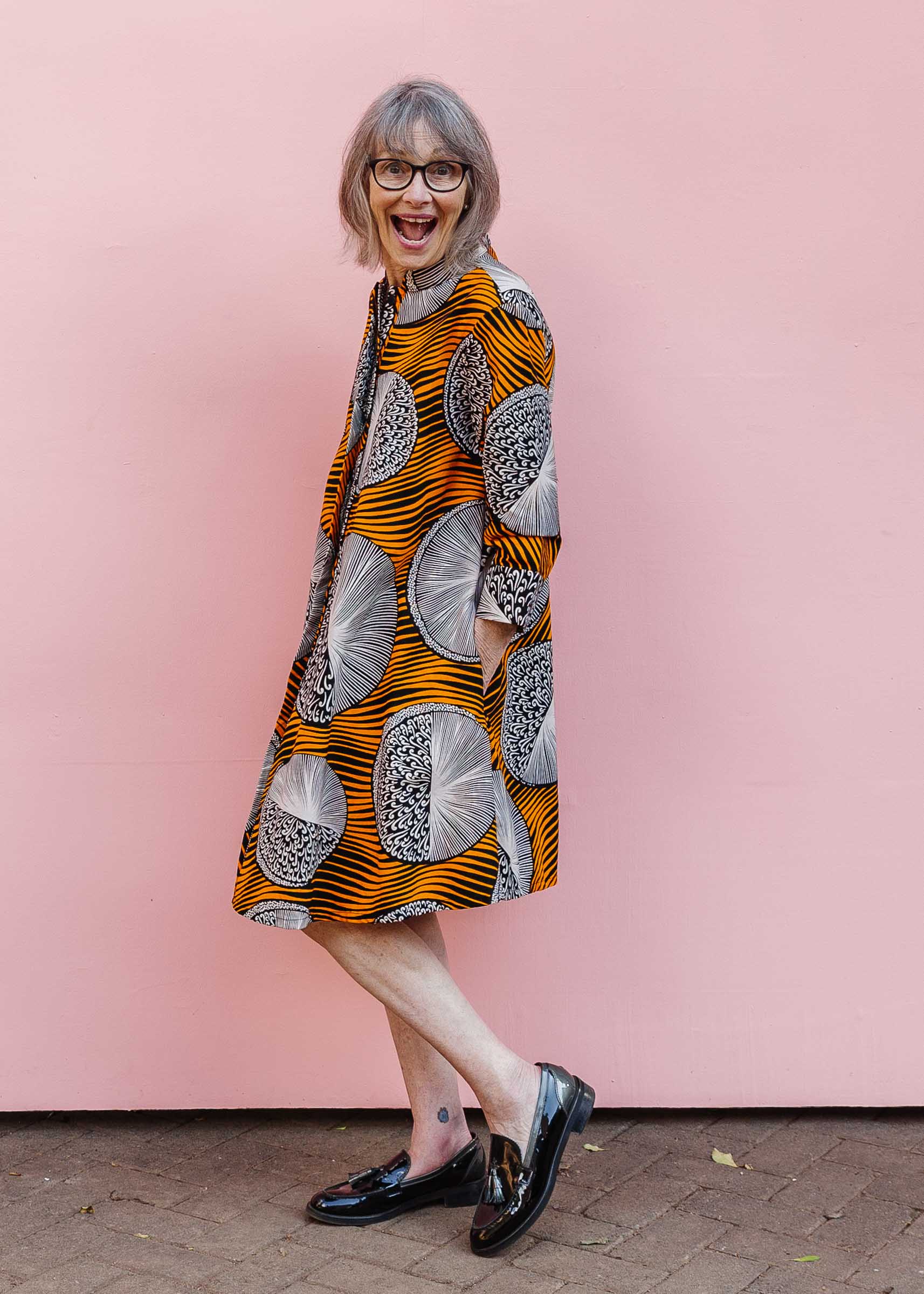 Model wearing black dress with orange stripes and black and white circles.