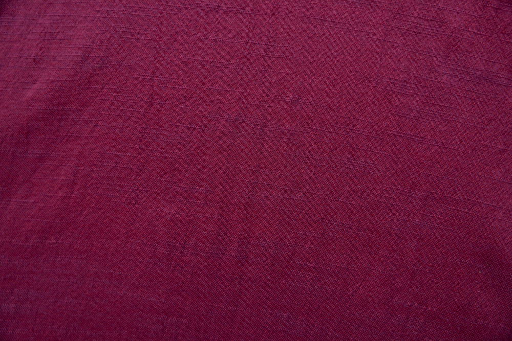 Close up display of burgundy linen dress, fabric.
