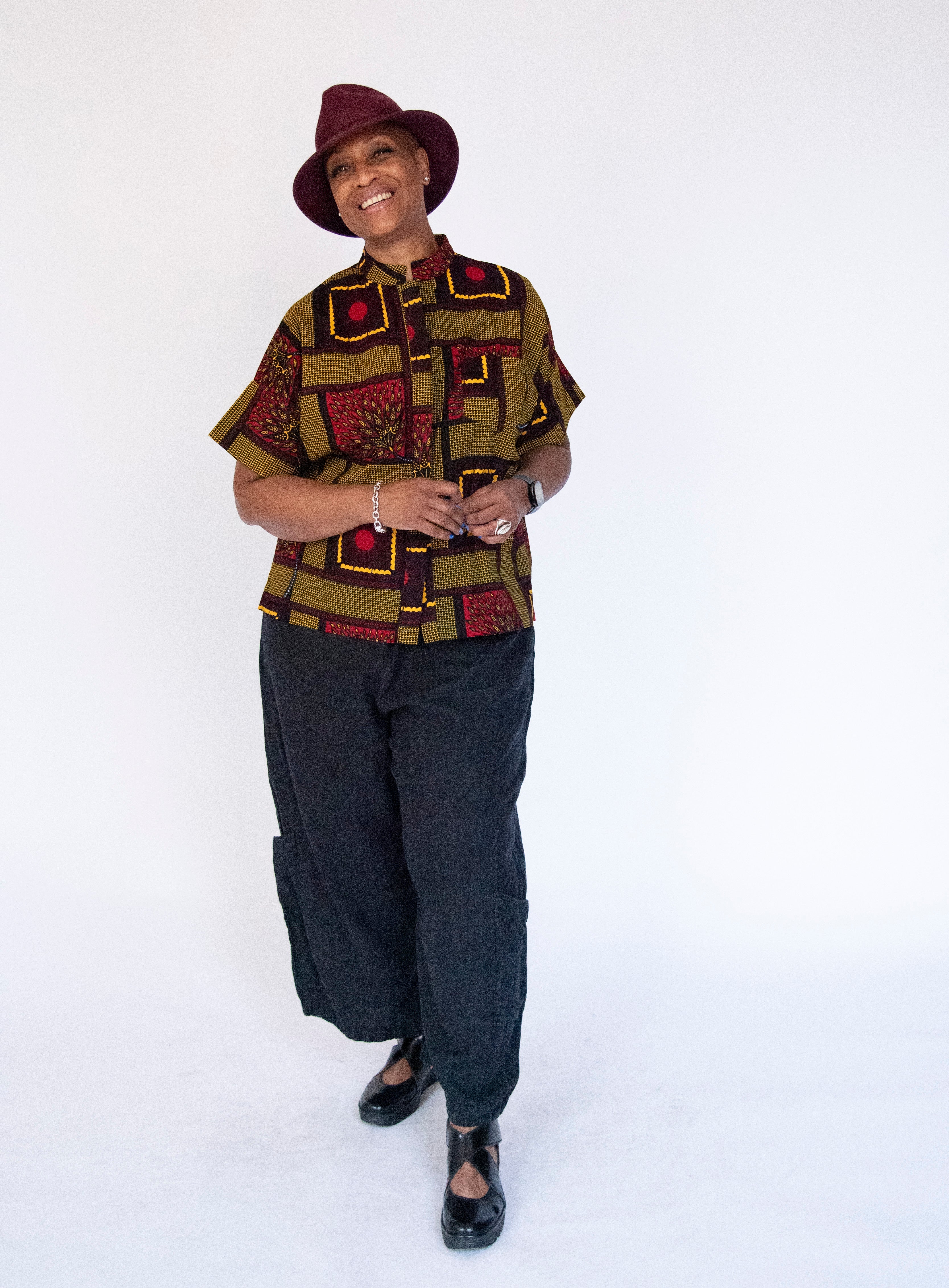 Model wearing yellow, red and black abstract print shirt.