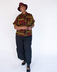 Model wearing yellow, red and black abstract print shirt.