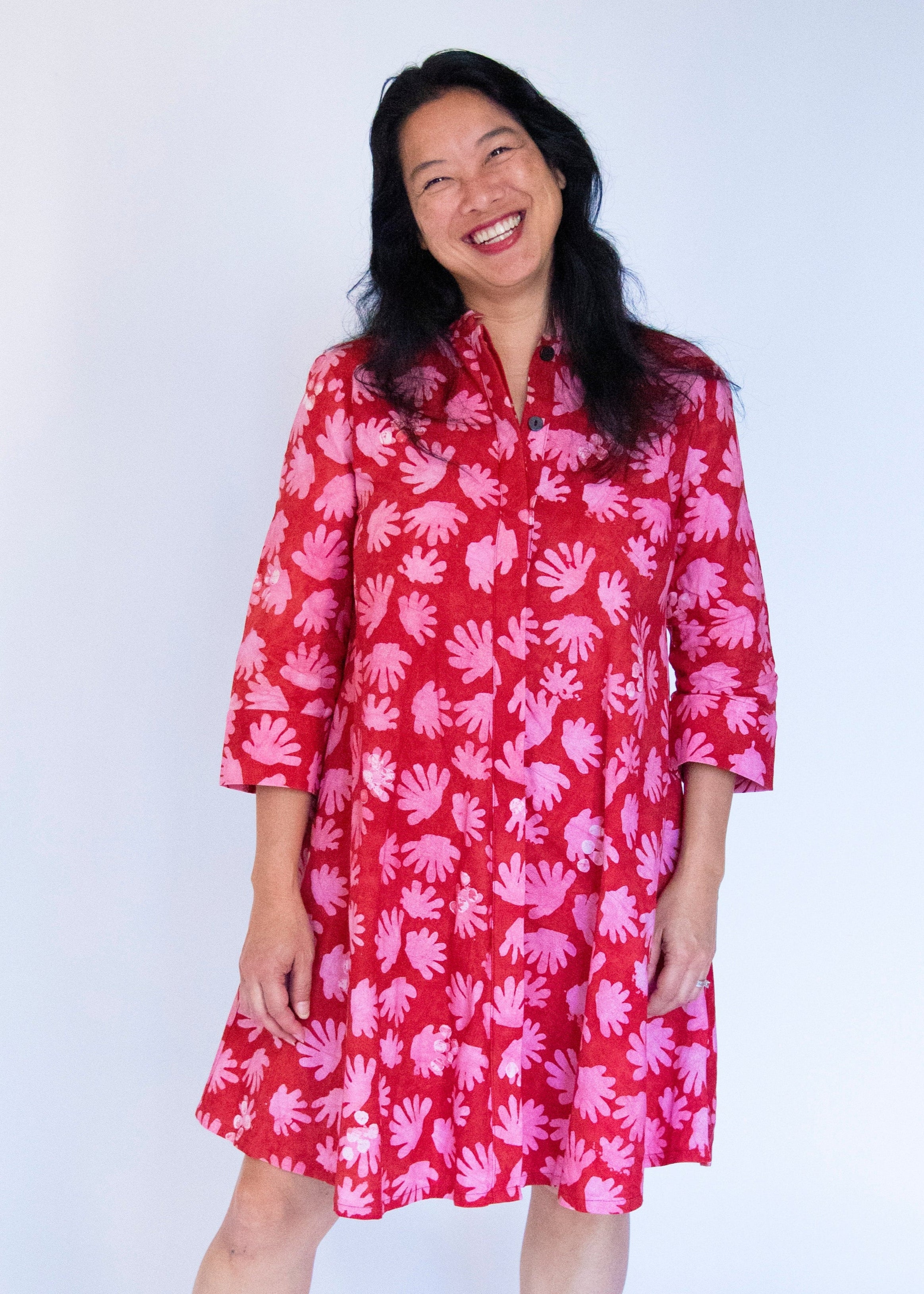 Model wearing red dress with pink flower print.