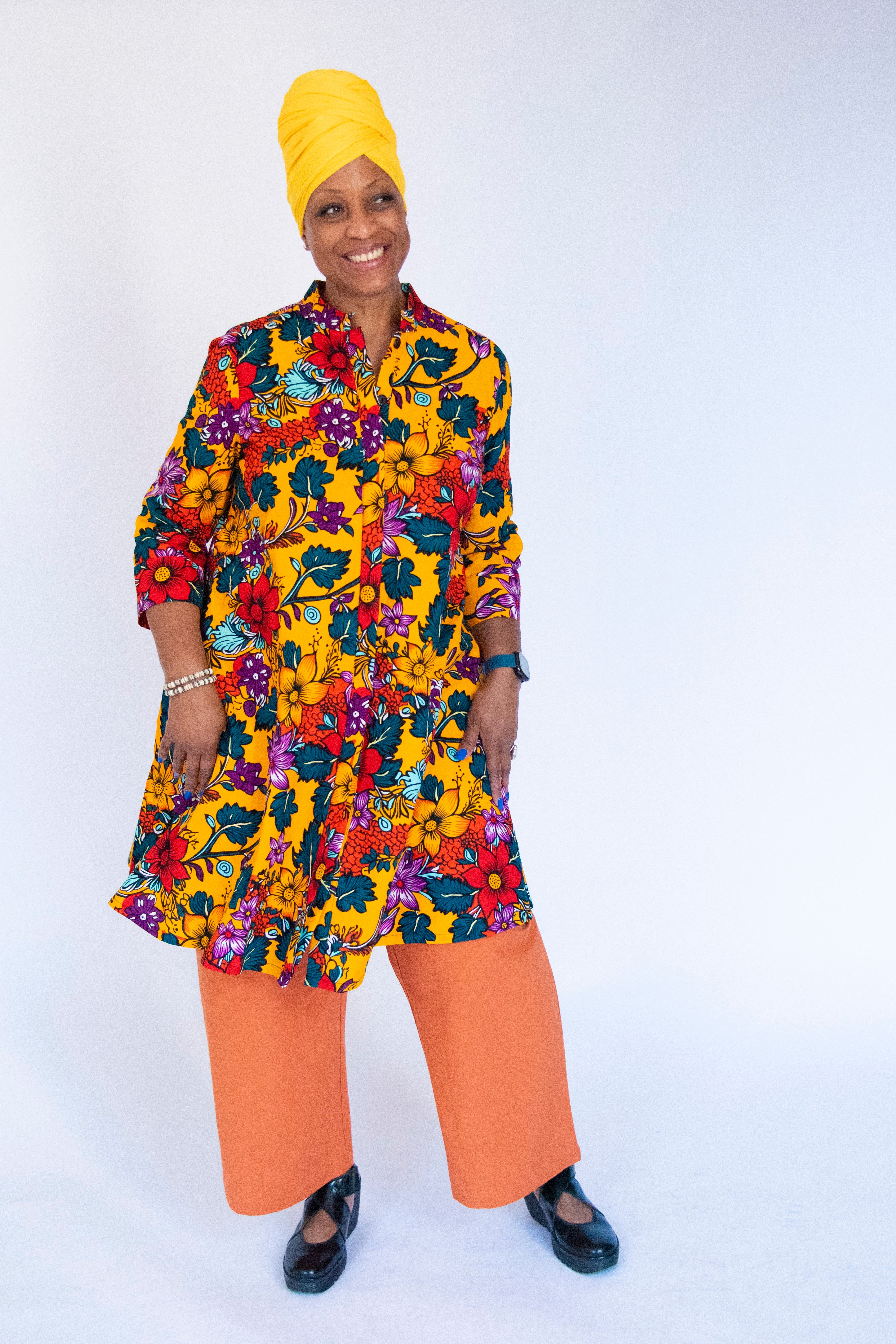 Model wearing yellow dress with multicolor floral print.