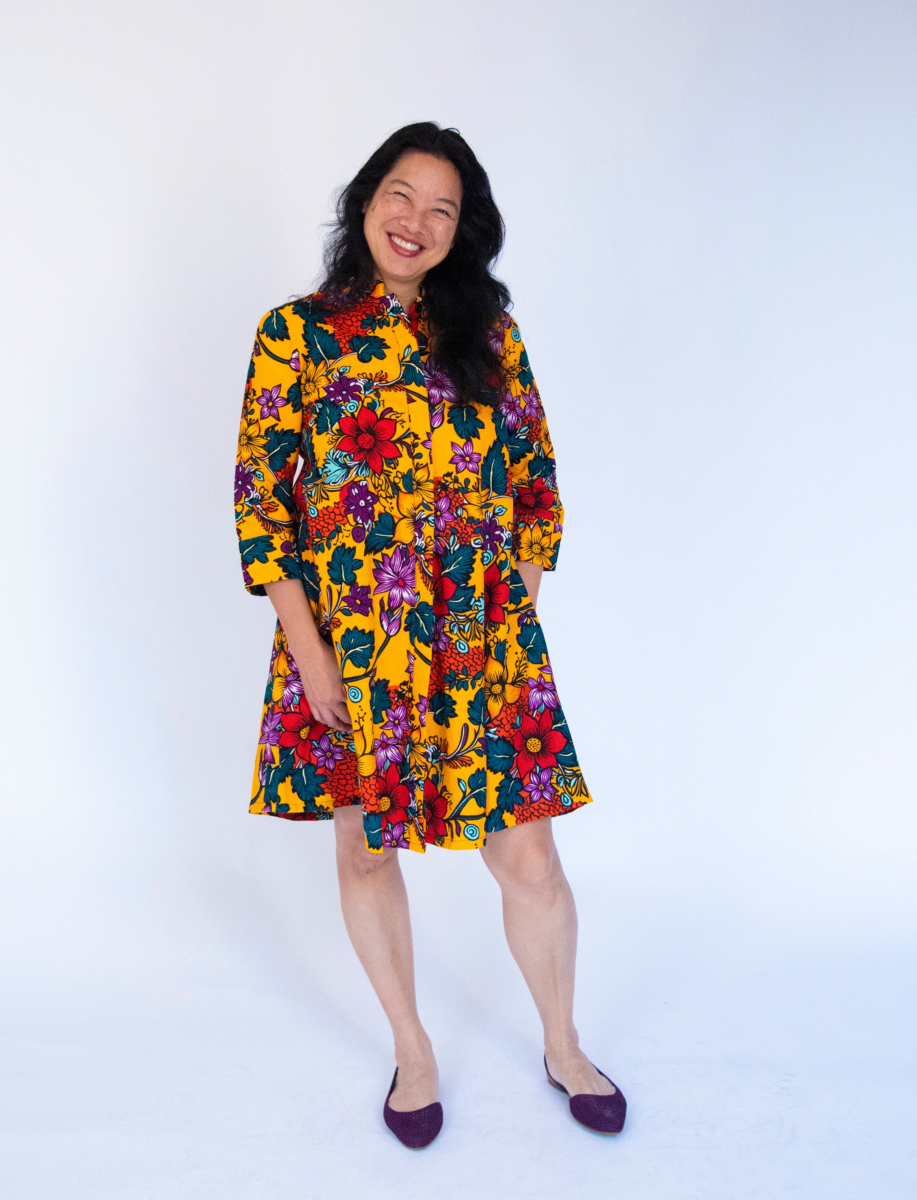 Model wearing yellow dress with multicolor floral print.