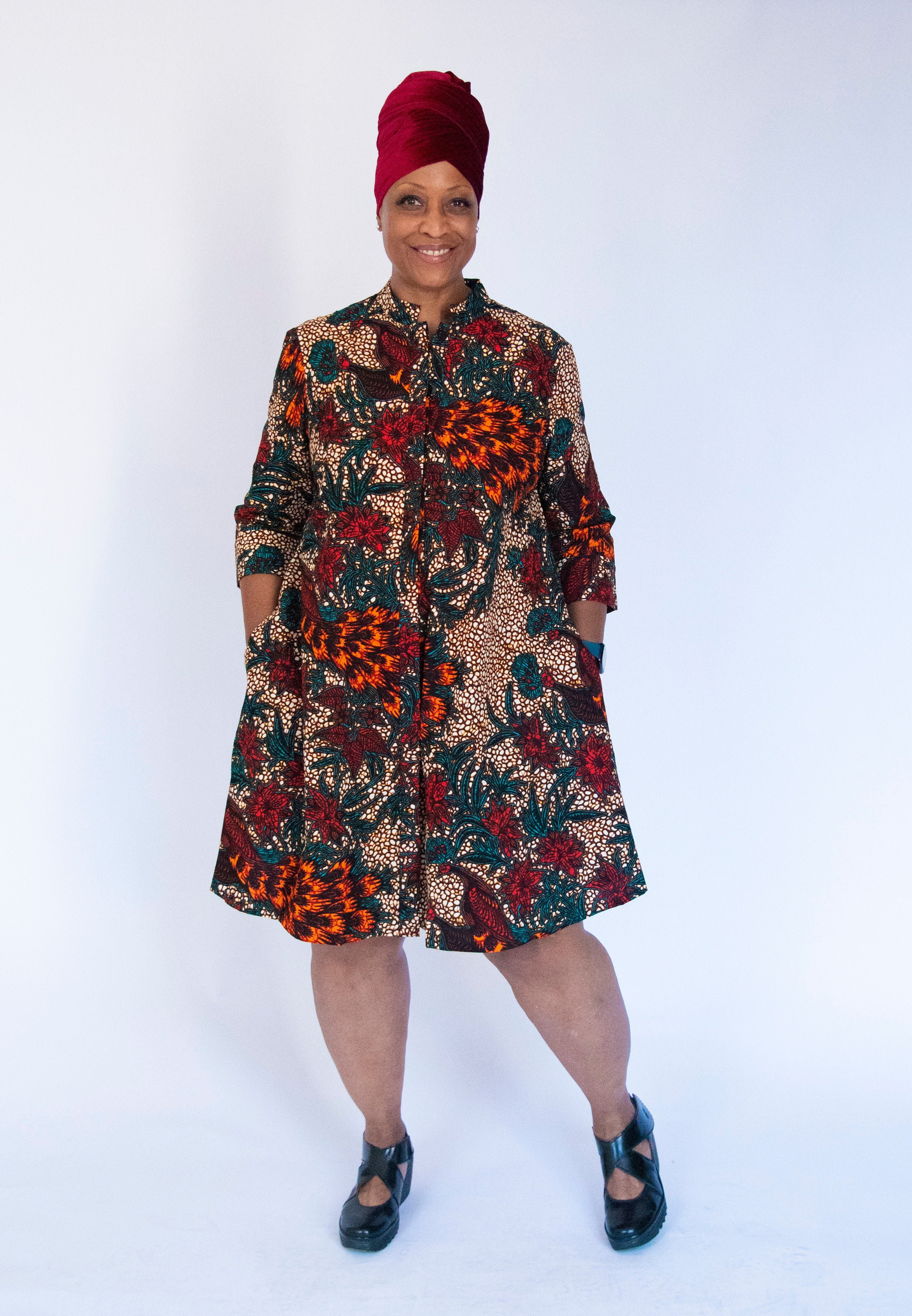 Model wearing orange, brown and green dress.
