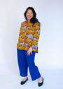 Model wearing long sleeved orange and purple geometric print shirt.