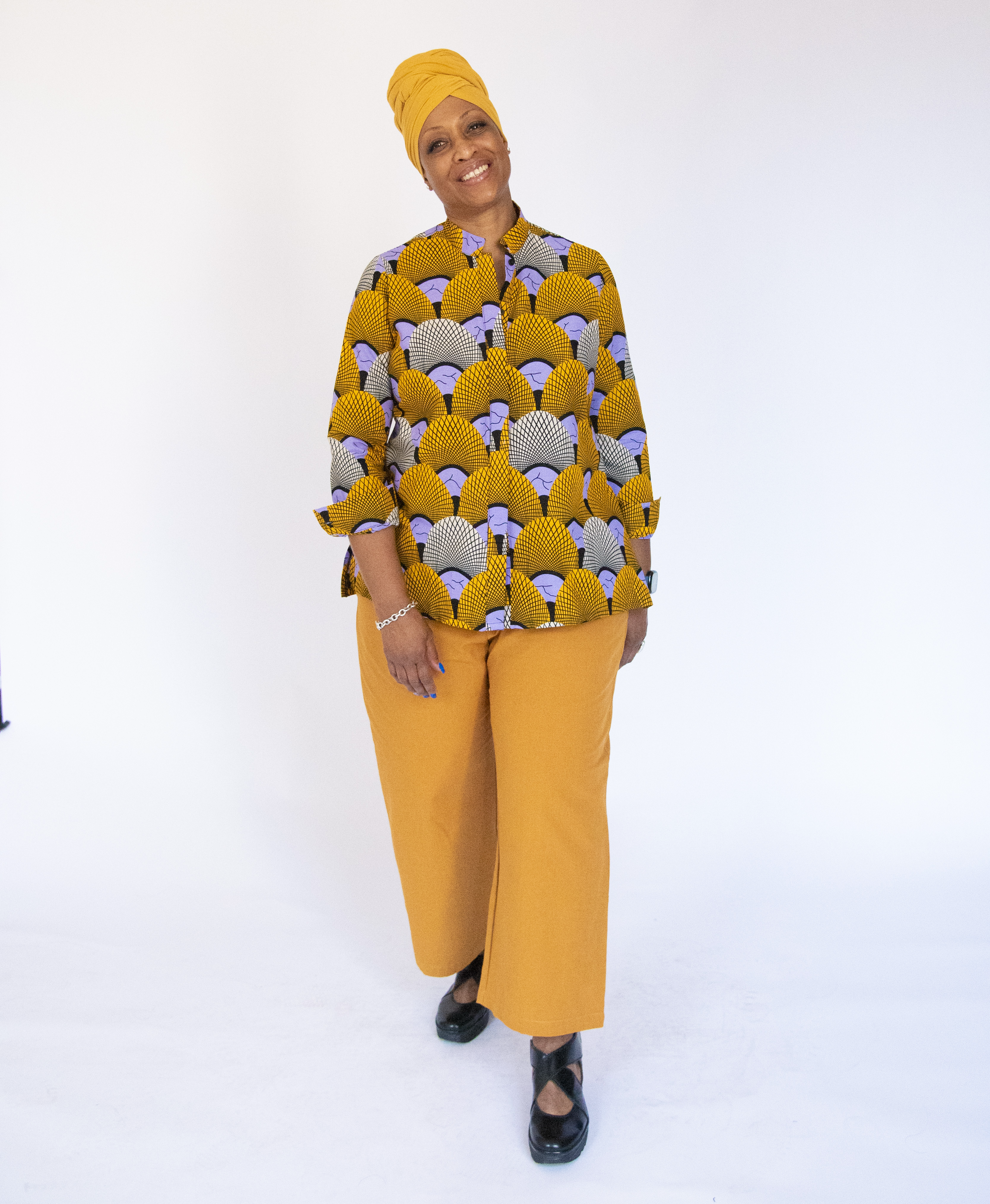 Model wearing long sleeved orange and purple geometric print shirt.