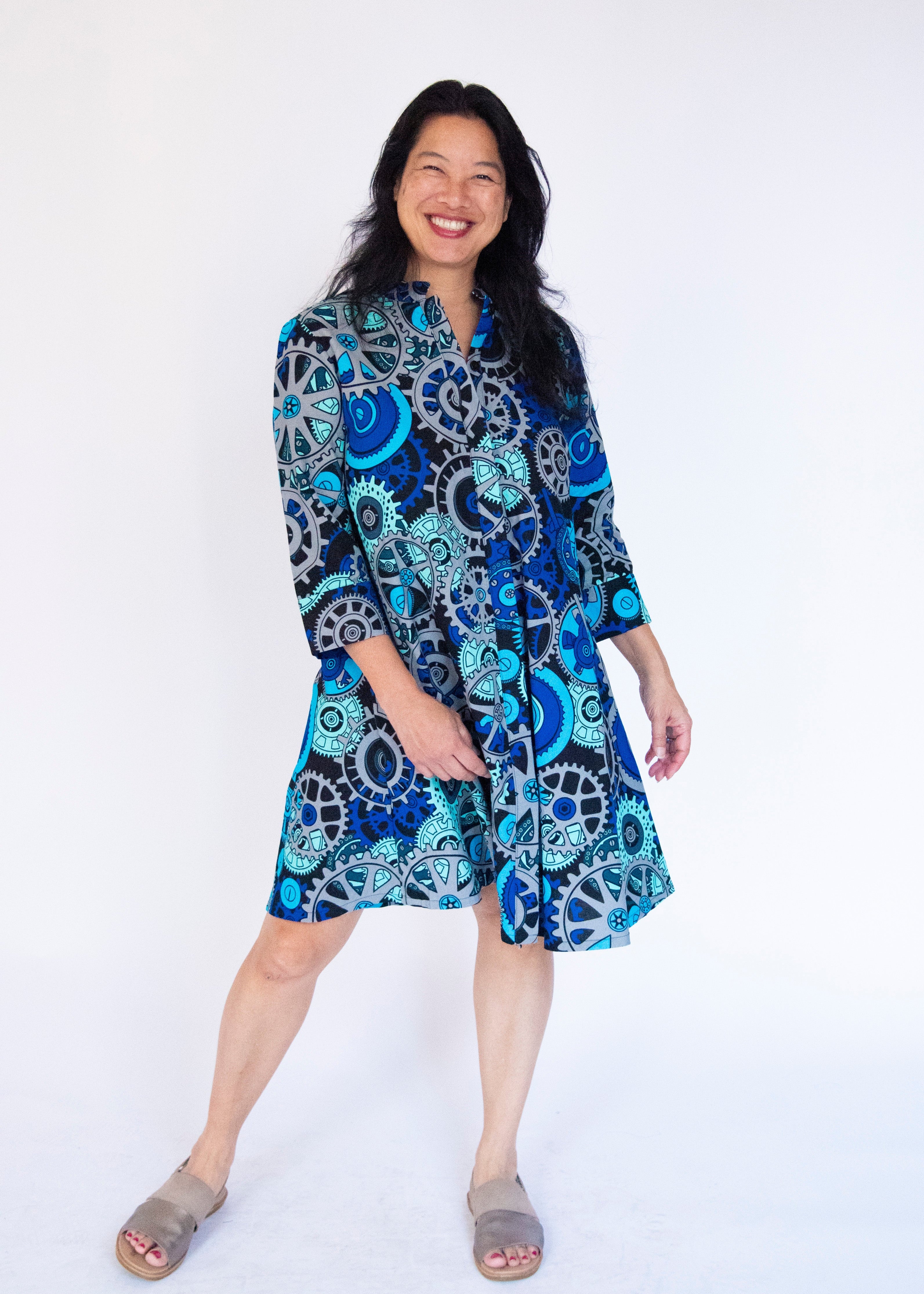 Model wearing dress with blue and grey gear graphic print.