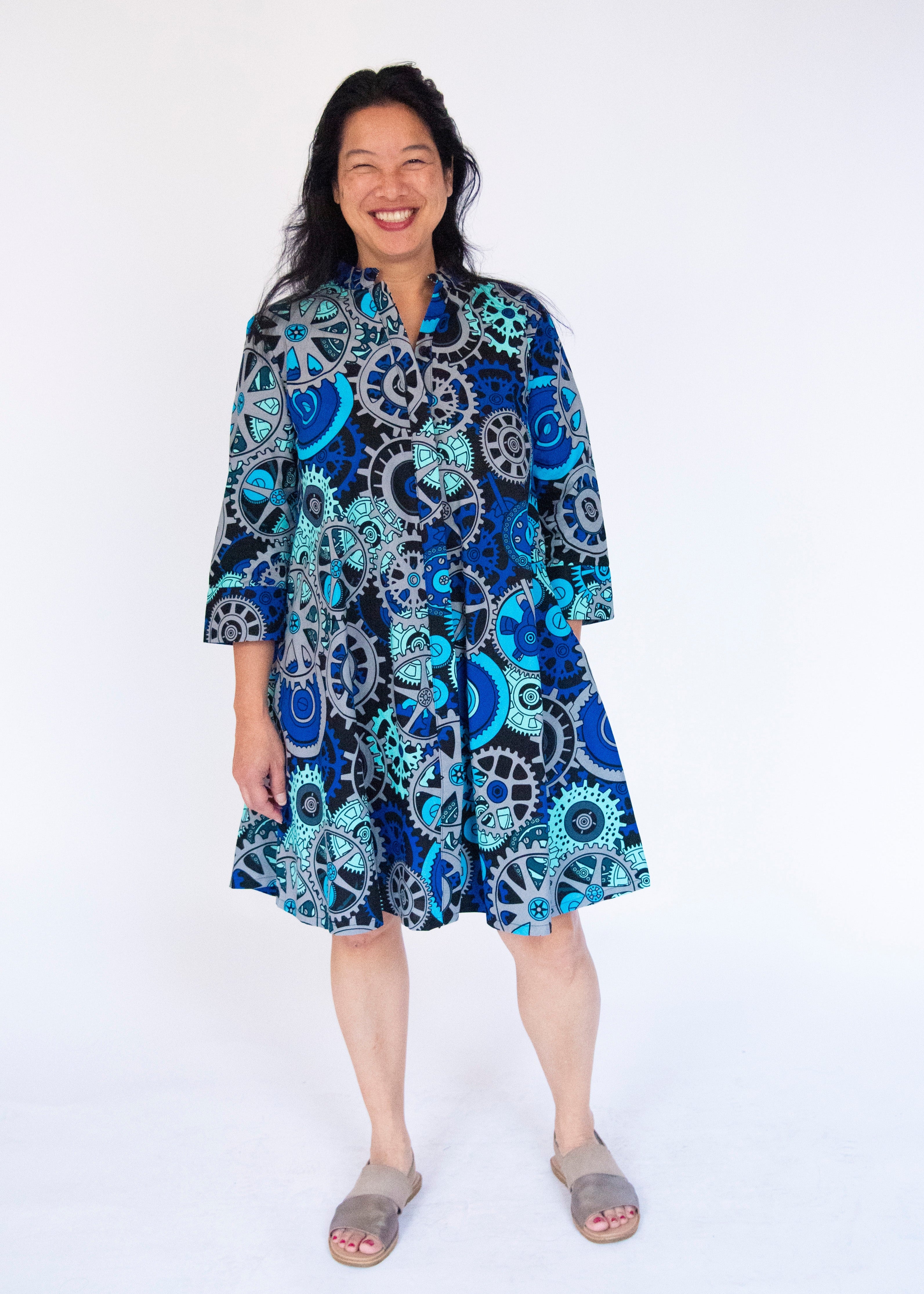 Model wearing dress with blue and grey gear graphic print.