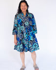 Model wearing dress with blue and grey gear graphic print.