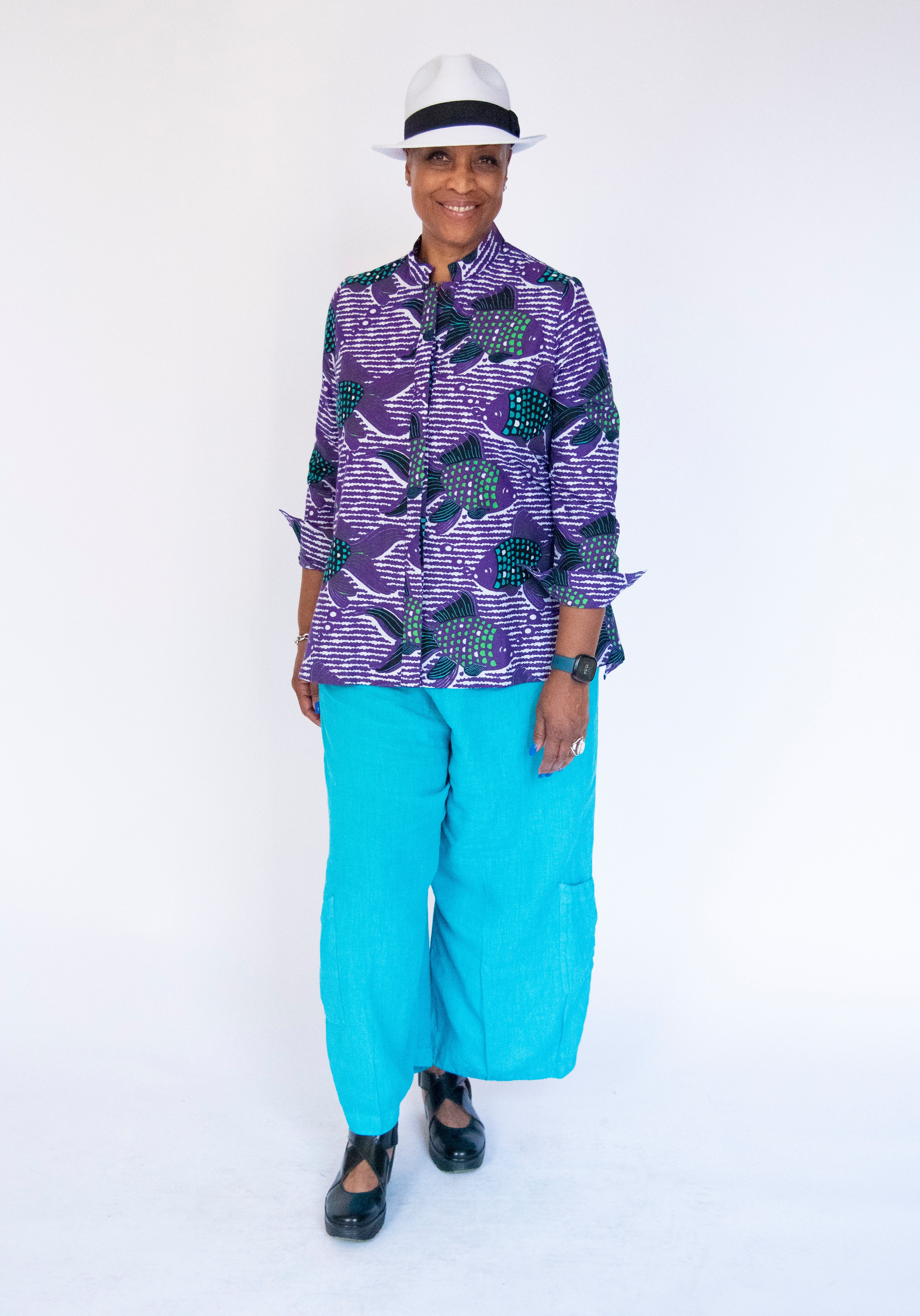 Model wearing long sleeved shirt with purple and green fish print.