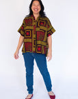 Model wearing yellow, red and black abstract print shirt.