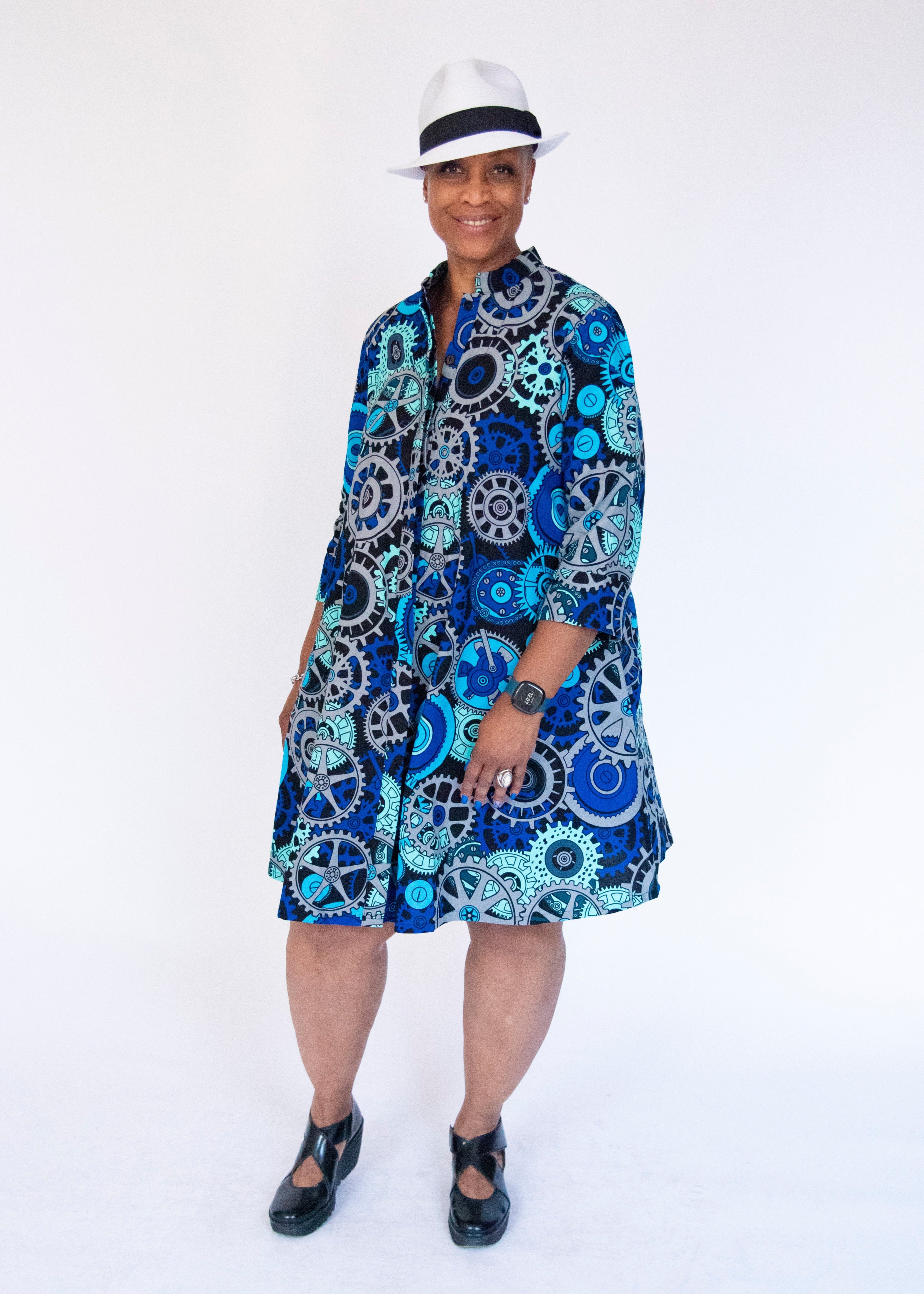 Model wearing dress with blue and grey gear graphic print.