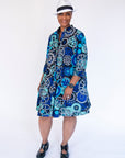 Model wearing dress with blue and grey gear graphic print.