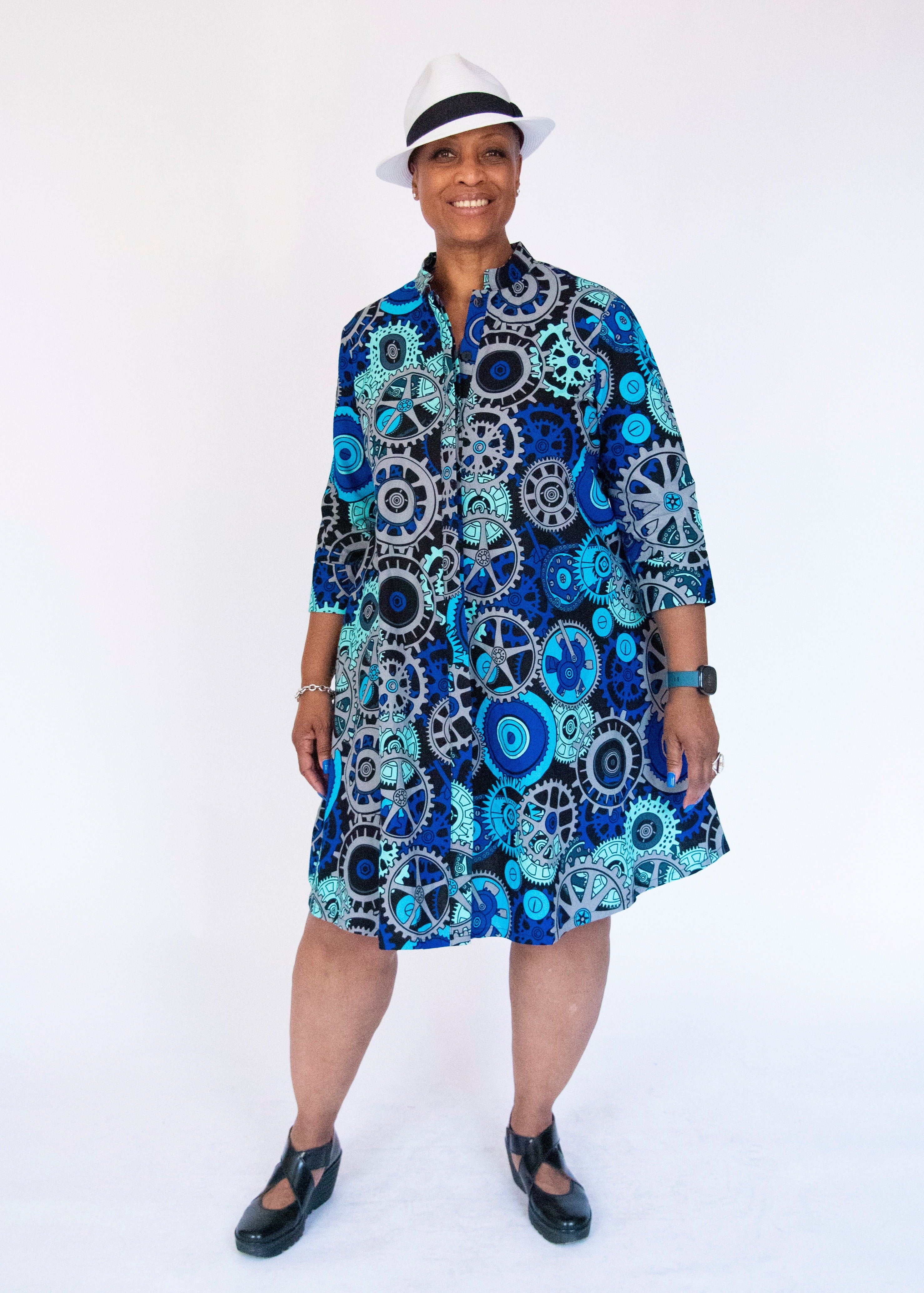 Model wearing dress with blue and grey gear graphic print.