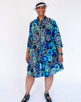 Model wearing dress with blue and grey gear graphic print.