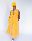 Model wearing yellow sleeveless dress with abstract pink print.
