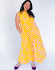 Model wearing yellow sleeveless dress with abstract pink print.